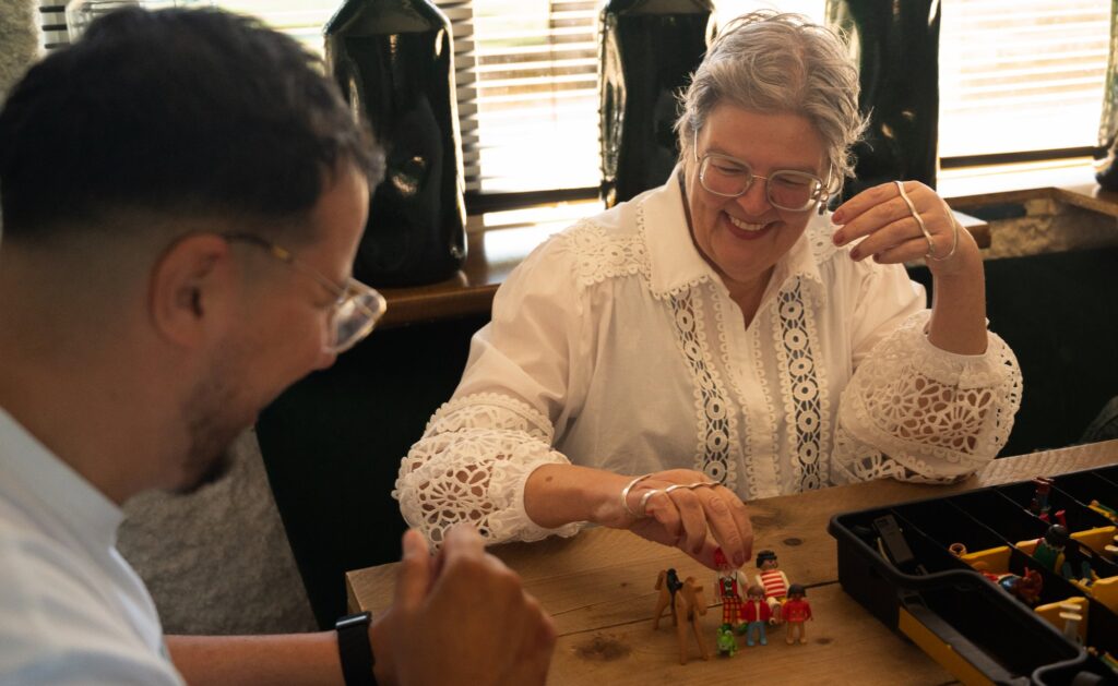 Begeleider en cliënt spelen samen met Playmobil aan de keukentafel