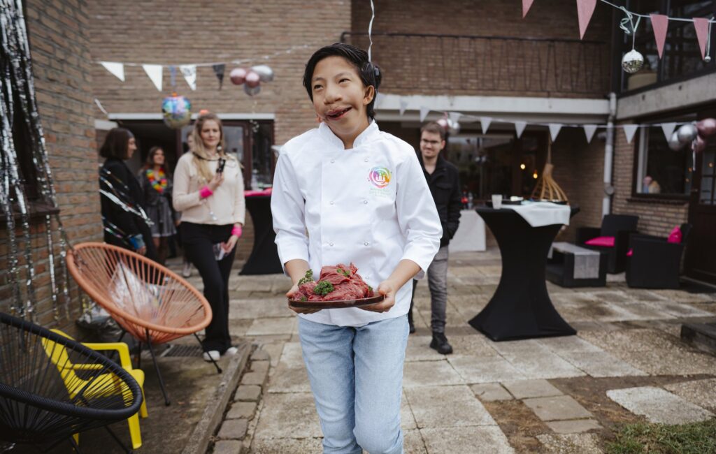 Jonge kok presenteert trots zijn gerecht tijdens een buitenactiviteit